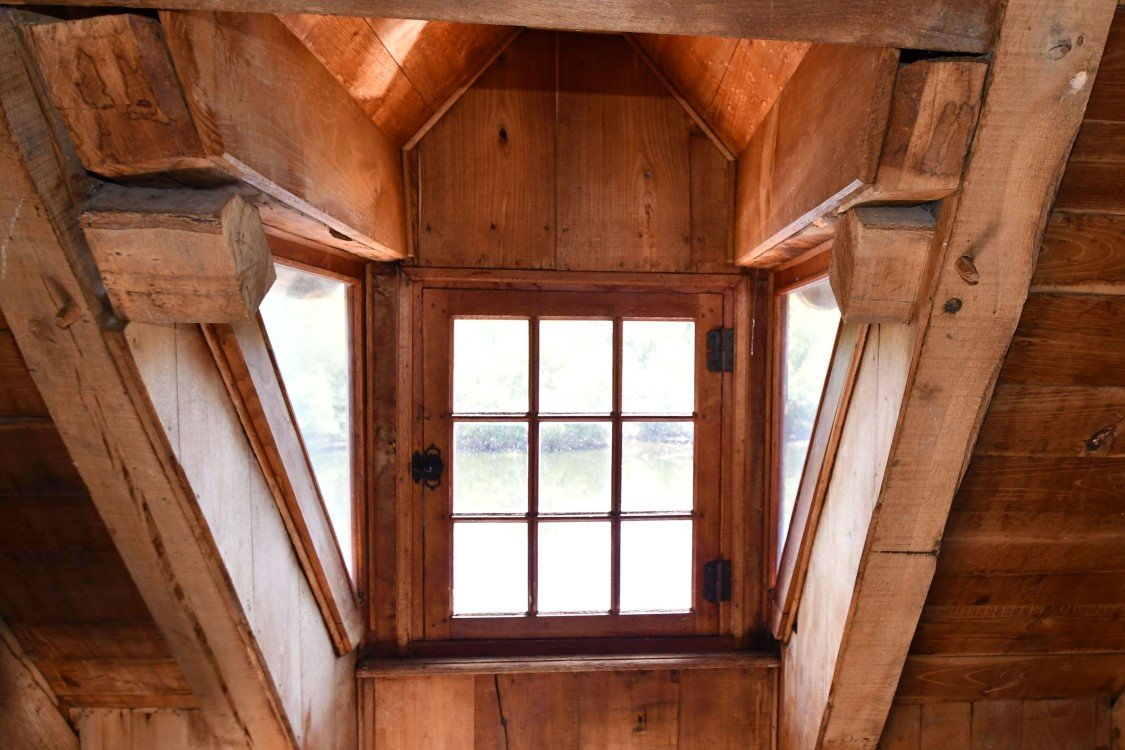 bedroom with sloping ceiling and a central window viewing greenery